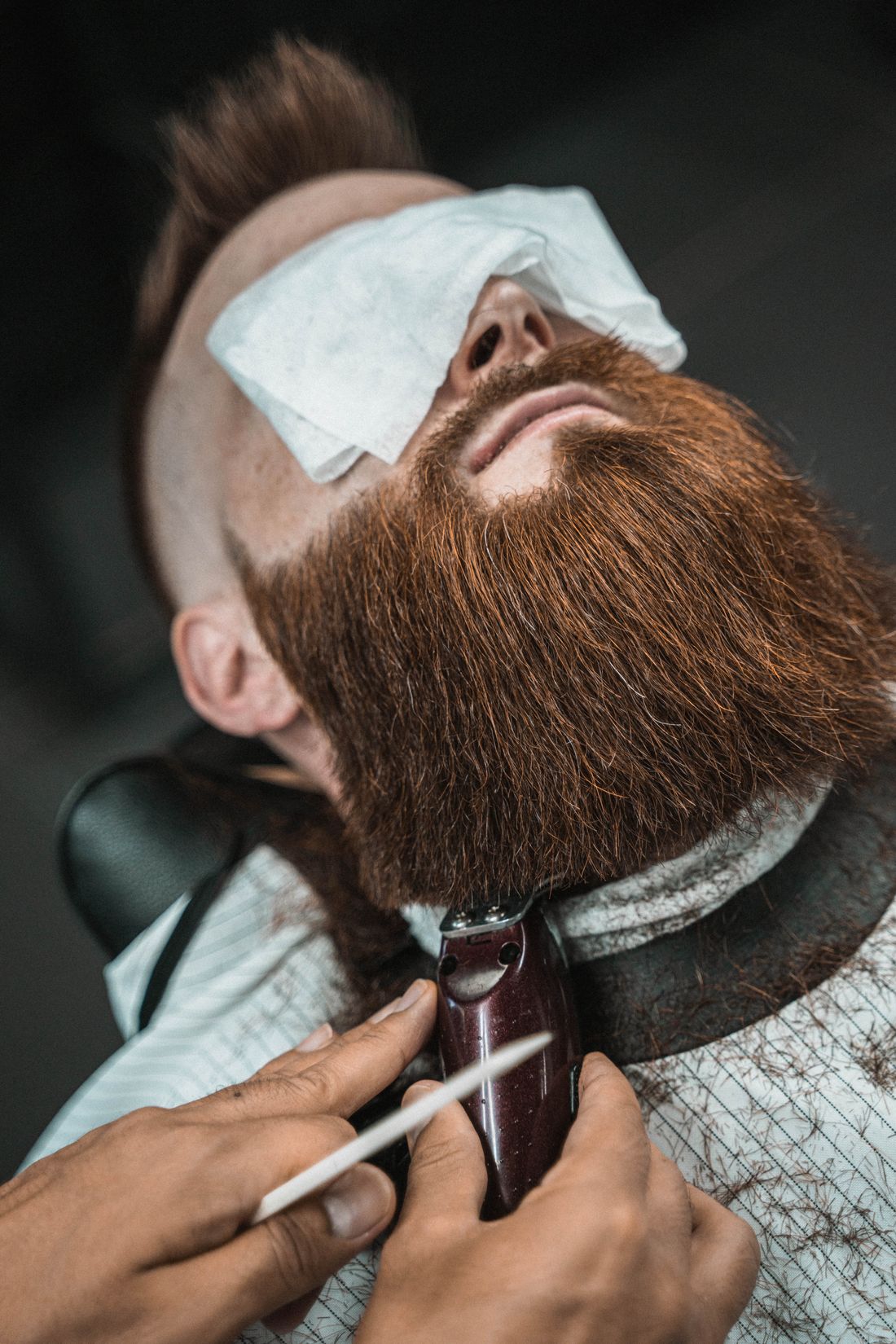 Barbero perfilando una barba roja con máquina
