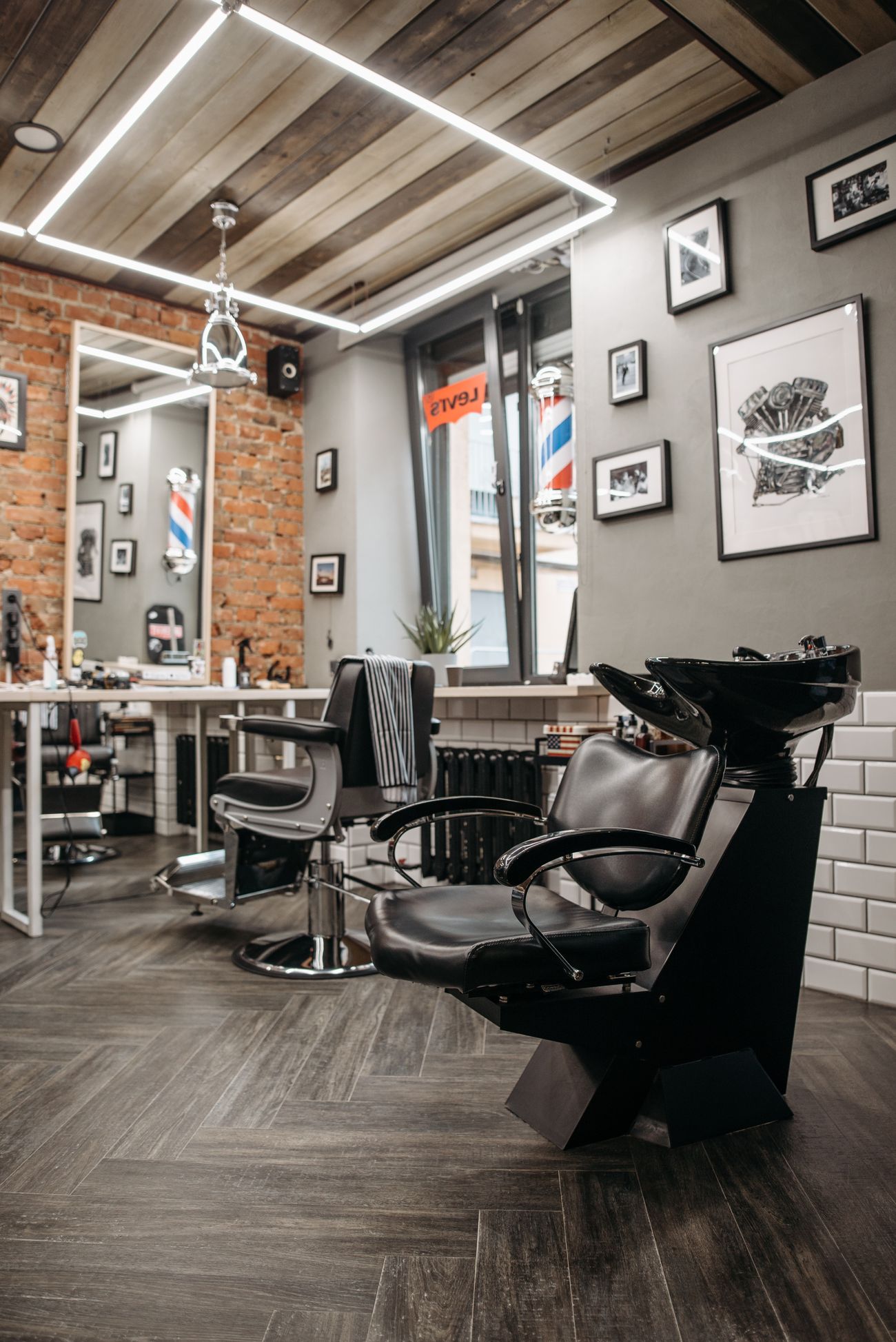 Barbería con sillas de cuero negro, espejo y poste de franjas